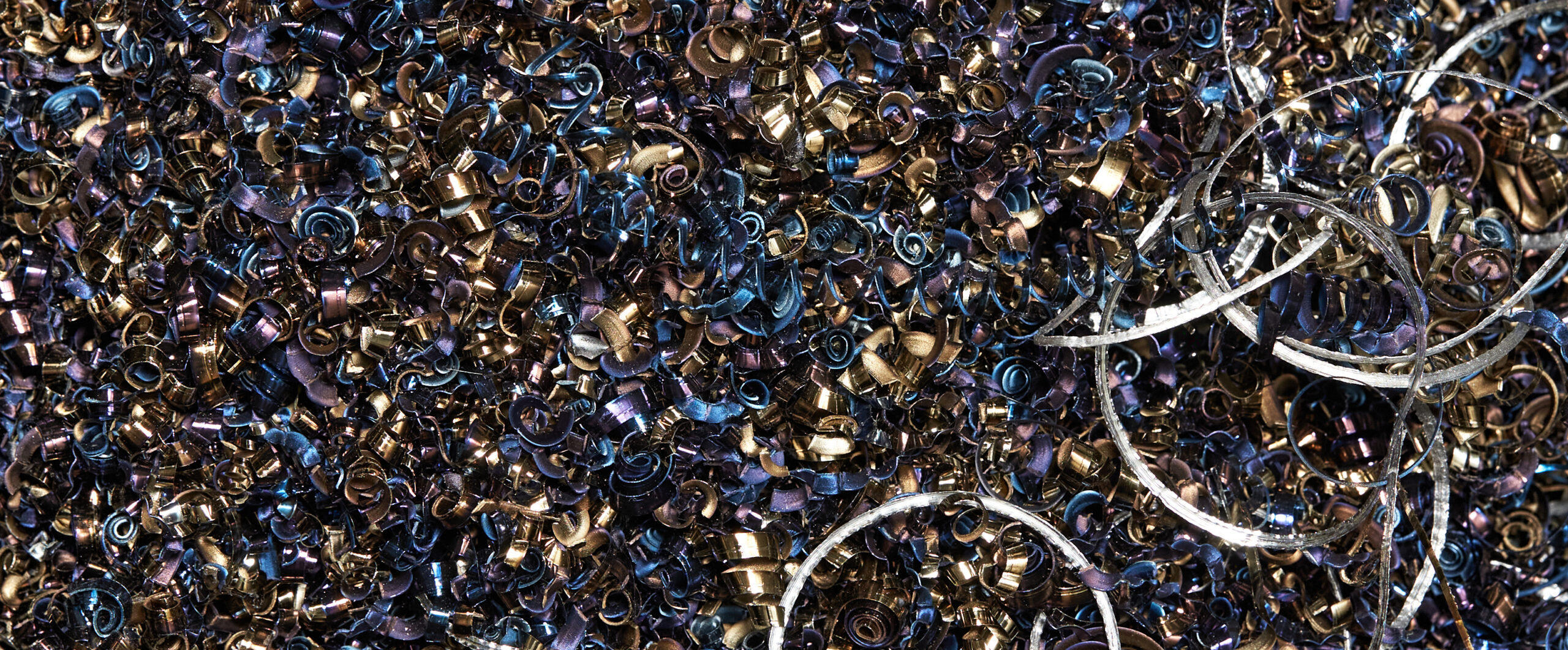 Closeup of steel and aluminum shavings of different colors.